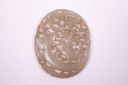 A Chinese mutton fat jade pieced oval panel, carved with a dragon, 6.5cm x 5.