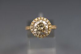 A yellow and white metal single stone diamond ring with diamond halo and shoulders.