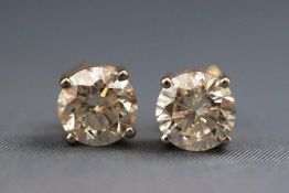 A modern yellow metal pair of single stone diamond studs.