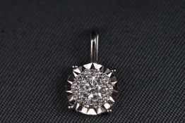 A modern white metal diamond cluster pendant. Stated weight of 0.25 carats. Stamped 750. 0.