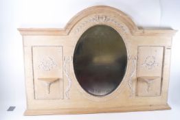A pine over-mantel mirror with classical bow and ribbon mouldings and two shelves,