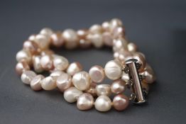 A long strand of cultured freshwater pale pink pearls together with a three row white and pink