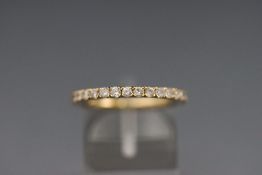 A modern yellow metal half hoop ring set with fifteen round brilliant cut diamonds.