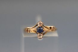 A yellow metal ring set with sapphire and colourless zircon. Stamped 18C. Size: I. 1.