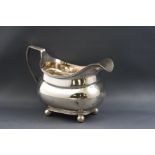 A George III silver milk jug of boat form on four ball feet, engraved with the monogram "W L",