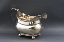 A George III silver milk jug of boat form on four ball feet, engraved with the monogram "W L",