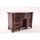 A doll's house mahogany serpentine desk, with an arrangement of ten drawers and central cupboard, 9.