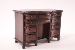 A doll's house mahogany serpentine desk, with an arrangement of ten drawers and central cupboard, 9.