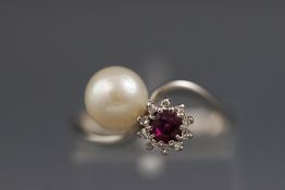 A modern white metal twist dress ring set with a ruby and diamond cluster and one cultured pearl.