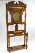 An early 20th century oak hallstand with central shield shape mirror over a bracket shelf,
