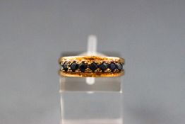 A yellow metal half hoop ring set with seven faceted cut sapphire.Hallmarked 9ct gold, 1977. 3.
