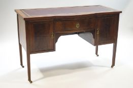 An Edwardian inlaid mahogany writing desk with inset red leather surface over a central drawer