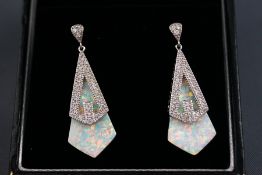 A modern white metal pair of drop earrings stylized as a kite shape with synthetic opal and cubic