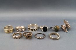A selection of ten silver rings consisting of signet and band rings with various abstract designs.