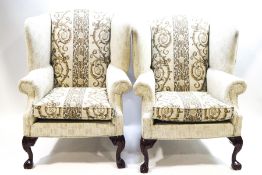 A pair of George II style wing back armchairs on mahogany claw and ball feet,