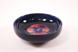 A William Moorcroft pottery dish, central design of a pansy on a deep blue ground,