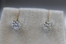 A modern white metal pair of single stone diamond stud earrings.