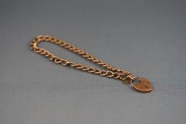 A rose metal curb bracelet with padlock and safety chain. Stamped 9ct. 5.