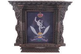 A presentation Gurkha embroidered panel within an ornately carved oak frame,