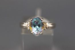 A modern ‘mystic’ topaz oval single stone ring with small three stone shoulders,