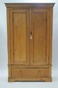 A Victorian pine wardrobe with two panelled doors above a drawer,