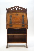 An Arts & Crafts oak bureau with cut out detail in the form of a bat and crescent moon,