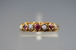A yellow gold carved half hoop ring set with opals and rubies.