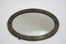 An Arts & Crafts oval wall mirror with silvered copper surround, 41cm x 56.