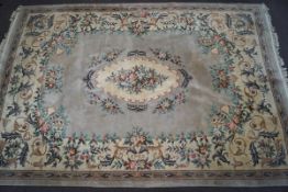 A large Chinese carpet with scrolling flowers on a beige field within one border,