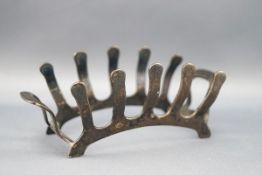 A silver small toast rack with four stylised flame shaped divisions,