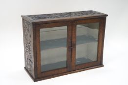 A Victorian oak glazed hanging cabinet, constructed from old timbers, bearing carved decoration, 51.