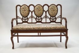 A pair of modern hardwood triple back settees with scrolling floral upholstery,