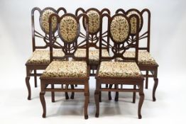 A set of five modern hardwood dining chairs with scrolling floral upholstery