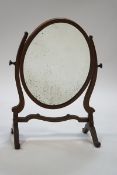 An Edwardian oval mahogany swing mirror,