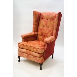 A George III style button back wing armchair with carved oak claw and ball feet,