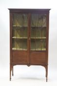 An Edwardian mahogany display cabinet with two glazed doors on square tapering legs with spade feet,