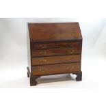 A George III mahogany bureau, the fall front enclosing a pigeon hole and drawer interior,