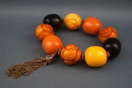 A modern vari-coloured and flower-carved bead bracelet imitating amber with a gilt-metal tassel