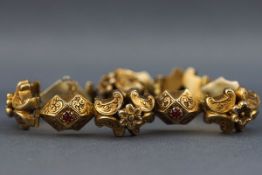 A Victorian silver gilt bracelet having hinged links with engraved floral design and set with red