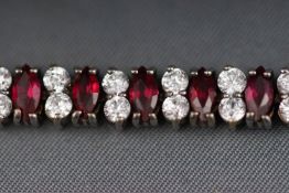 A white metal line bracelet set with red and white paste stones.