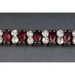 A white metal line bracelet set with red and white paste stones.