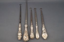 Five Victorian silver handled button hooks, each with an elaborately embossed handle,