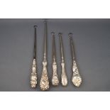 Five Victorian silver handled button hooks, each with an elaborately embossed handle,