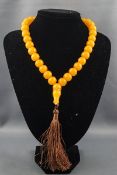 A yellow bead necklace with a brown silk tassel imitating amber