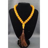 A yellow bead necklace with a brown silk tassel imitating amber