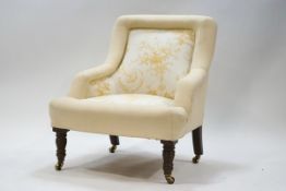 A Victorian style armchair on turned wood front legs and brass casters,