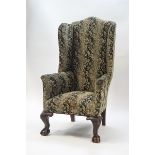 A 19th century wingback armchair with carved cabriole legs on ball and claw feet