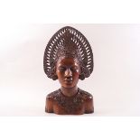 A carved hardwood bust of a Balinese lady weaaring an elaborate headdress,