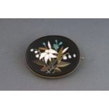 A Victorian gold and pietra dura oval brooch depicting a flower spray with forget me nots and