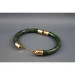 An Oriental green and black mottled hardstone hinged-bangle imitating jade with yellow metal mounts